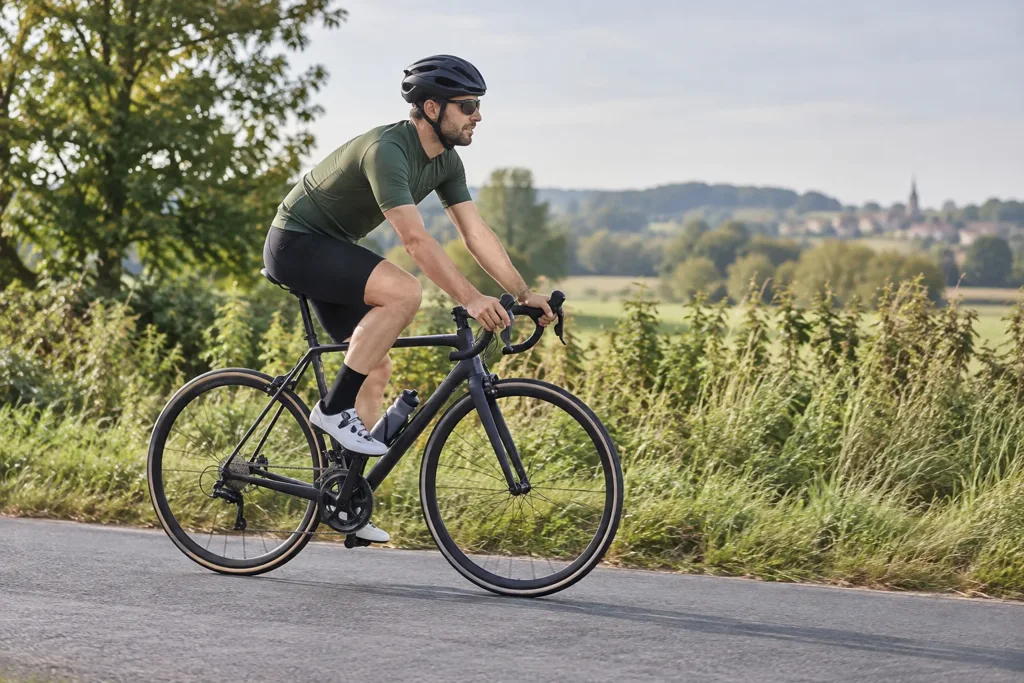 Illustration d’un cycliste fictif vu de profil sur une route rurale, montrant sa position sur le vélo.